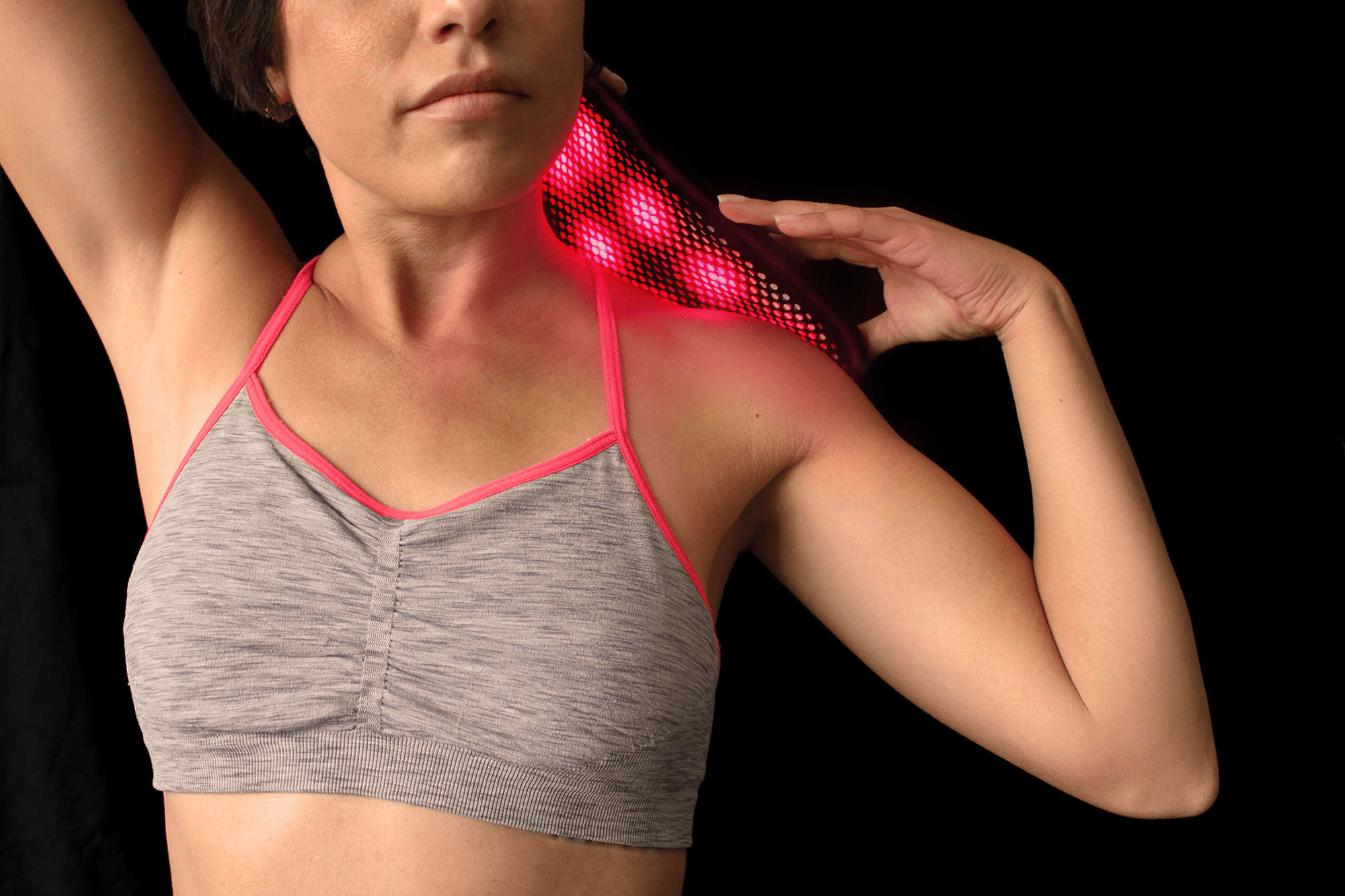 Woman using DNA Vibe's red light therapy for neck pain