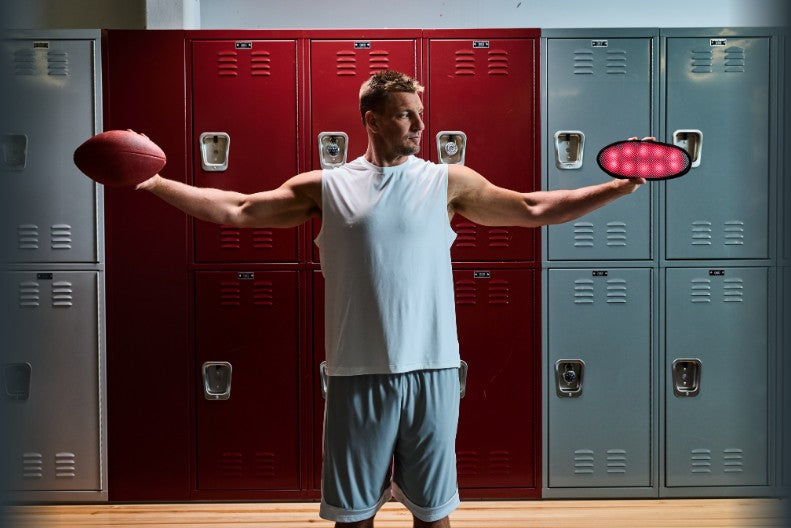 Rob Gronkowski in a locker room holding a football and the DNA Vibe light pad