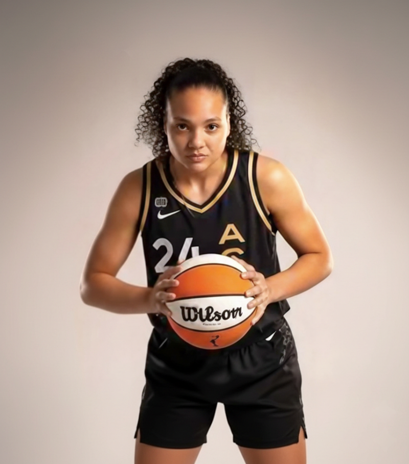 Person wearing a basketball uniform holding a Wilson basketball